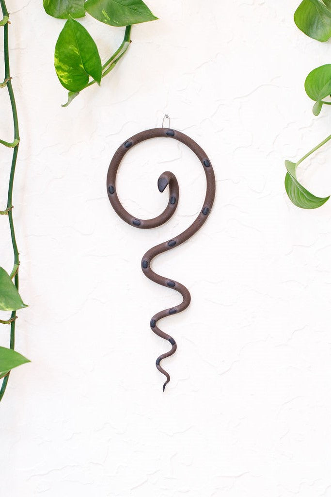 Simple contemporary ceramic snake wall decoration, with the top of the snake shaped loosely like a question mark and the tail hangs down in an organic s curve. This snake is Saul, dark brown with black glazed head and dots.