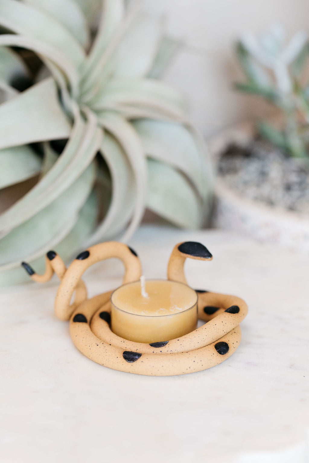 Organically coiled speckled tan clay snake with black head and dots. This colorway is Sammy. Styled with a beeswax tea light that sits in the center of the coil.