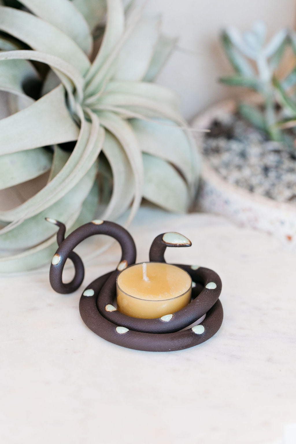 Organically coiled black clay snake with glazed turquoise head and dots. This colorway is Stevie. Styled with a beeswax tea light that sits in the center of the coil.