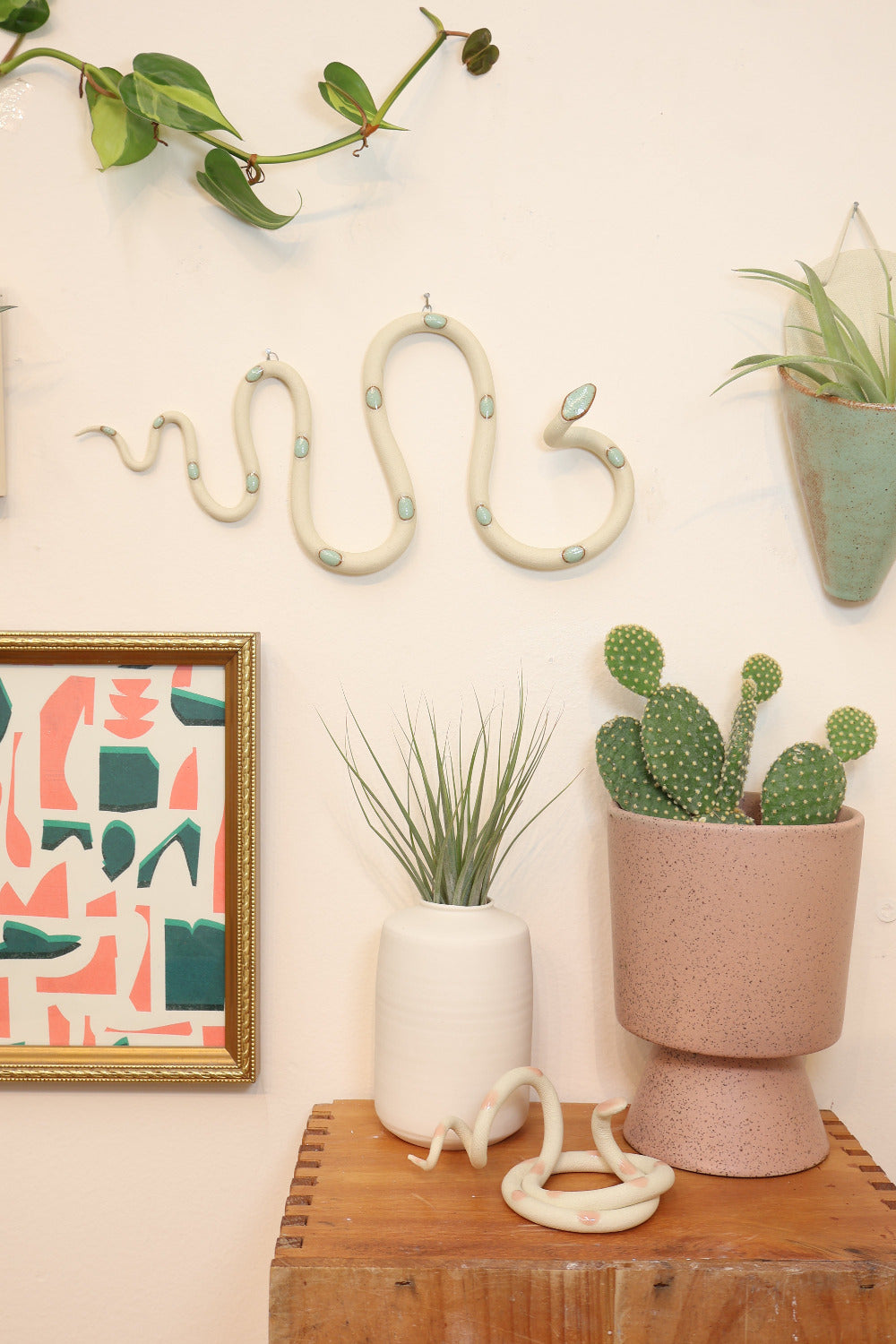 Decorative items including a snake figure, plants, and a framed abstract art piece on a light surface.