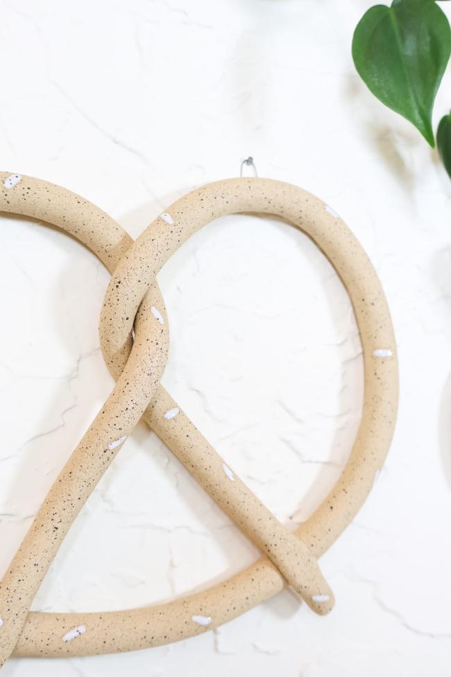 Close up of the ceramic pretzel sculpture showing the speckled clay base and white glazed salt sprinkles