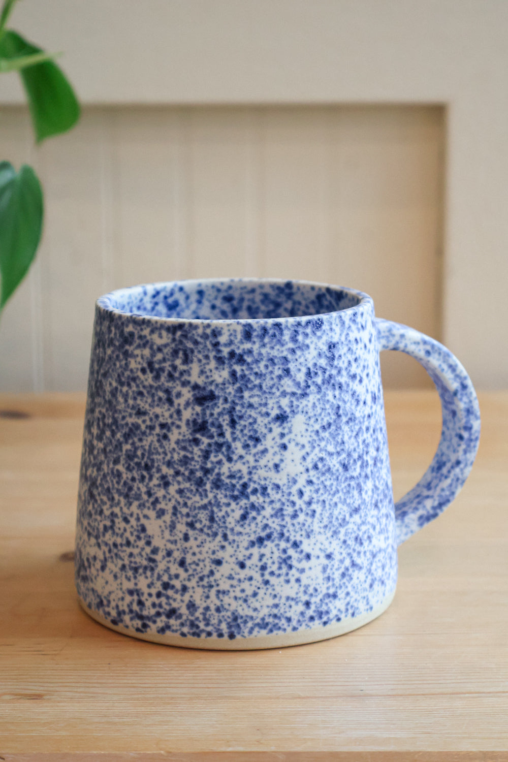 Speckled blue and white glazed mug with a cylindrical shape that is slightly more narrow at the top. 
